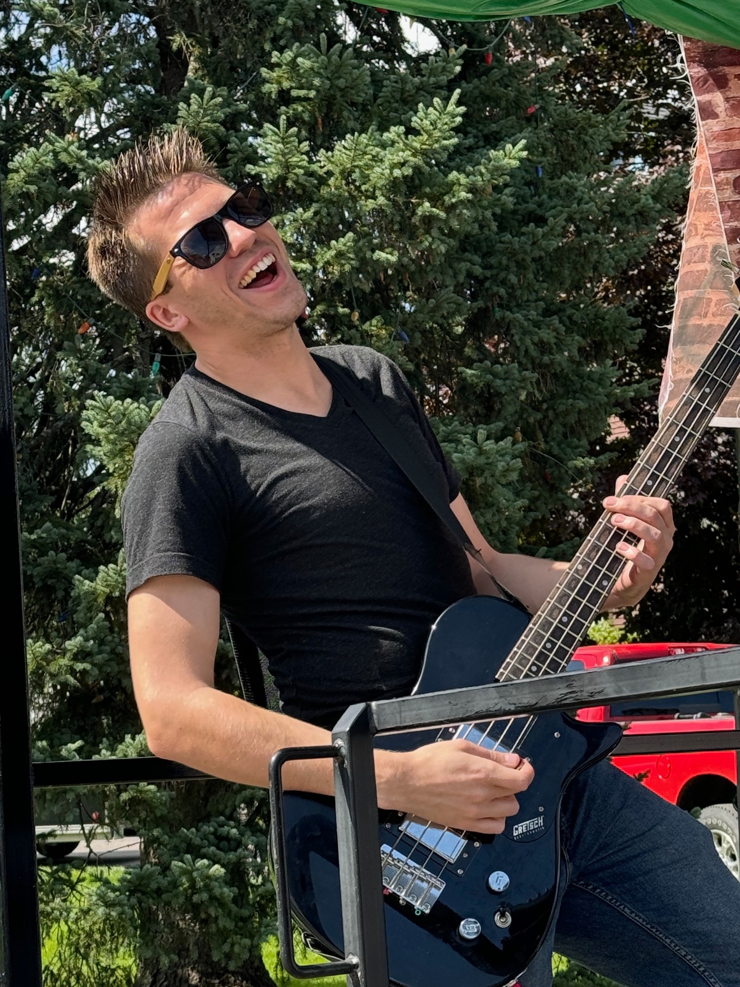 Tom Jordan laughing while playing bass onstage outdoors